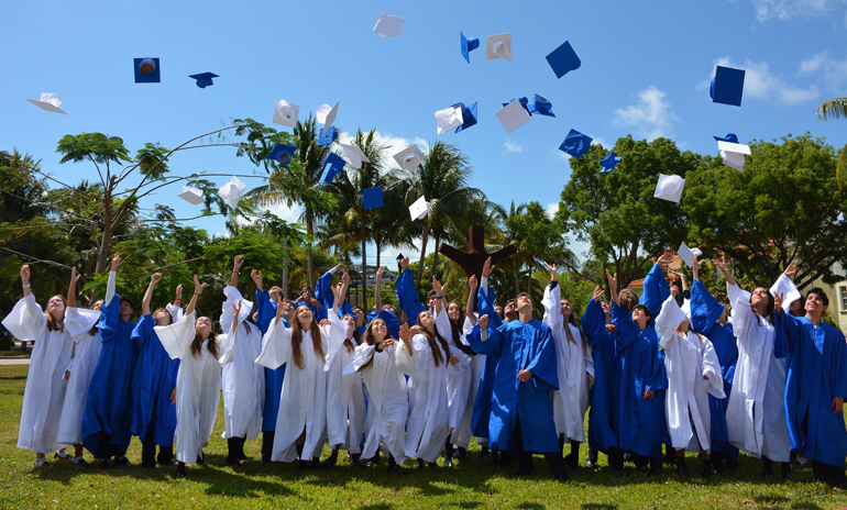 Eighth grade students from St. Agnes Academy throw their caps up in graduation celebration.