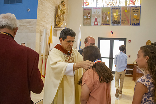 Father Juan Carlos Paguaga presents Gena Escanaverino, from Blessed Trinity School in Virginia Gardens, with a medal during the All Catholic Conference All Star Mass held at St. Agnes Church in Key Biscayne on May 5.