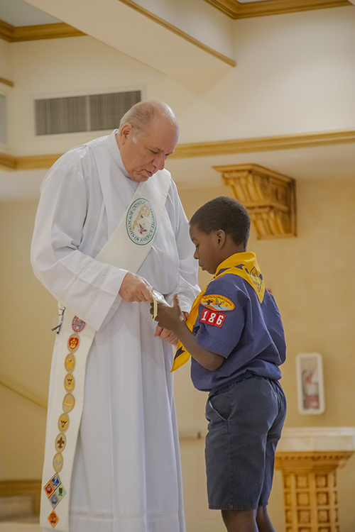 Bryce Griffiths, Cub Scout from St. Bartholomew Church, Miramar, receives the Light of Christ emblem from Deacon Emilio Blanco during the Archdiocese of Miami's Catholic Scouting Presentation Mass.