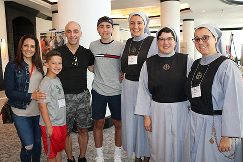 George Frem de Boston, su esposa Rania y sus dos hijos se reúnen con miembros de los Siervos de Cristo la Luz de Dartmouth, de Massachusetts, durante la convención maronita en Miami. La comunidad religiosa, que celebra su décimo aniversario, es la primera congregación religiosa maronita establecida en los Estados Unidos. Con la familia posan desde la izquierda las Hnas. Therese Maria Touma, la Hna. Marla Marie Lucas, fundadora de la comunidad y la Hna. Natalie Sayde.