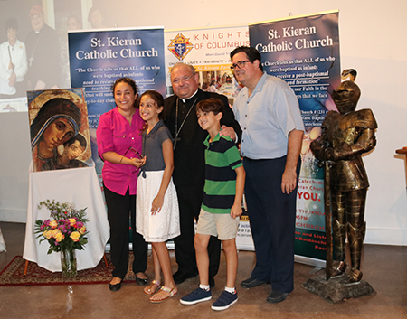 El Obispo Peter Baldacchino posa con la familia Botero, feligreses de St. Kieran. A la izquierda Claudia (la mamá) y Alexandra. A la derecha Julián y Thomas (el papá). La familia Botero regresó a la Iglesia después de escuchar una homilía del Obispo Baldacchino donde los invitaba a regresar sin importar lo que hubiera pasado. “Era un mensaje dirigido a nosotros que inmediatamente nos cautivó”, dijo Thomas, recordando ese momento hace cuatro años.