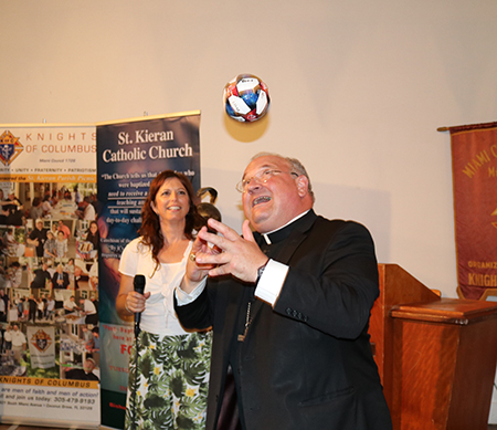 El Obispo Peter Baldacchino juega con una pequeña pelota de fútbol que le regaló una feligresa de St. Kieran, durante la celebración de despedida.