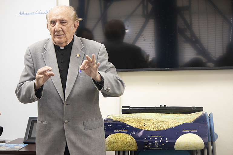 Parado al lado de un mapa lunar, el Padre Jesuita Pedro Cartaya, aficiondado de astronomía en la escuela secundaria de Belén, recuerda el momento en que el hombre pisó la superficie de la luna por primera vez.