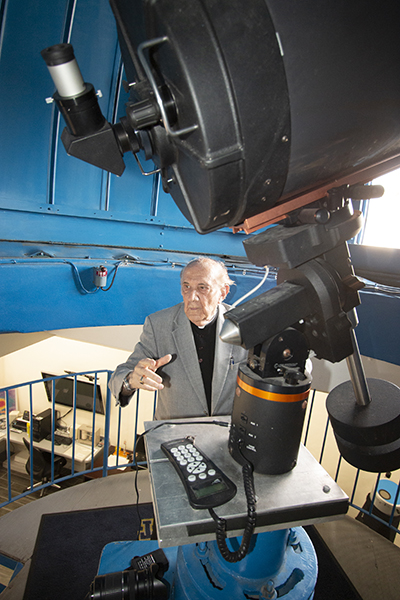 El padre Jesuita Pedro Cartaya describe los atributos del observatorio de la escuela de Belén en Miami. Está parado junto al telescopio de 16" con una cámara CCD (digital) para astrofotografía. Belén es la única escuela en los Estados Unidos equipada con ese tipo de telescopio.