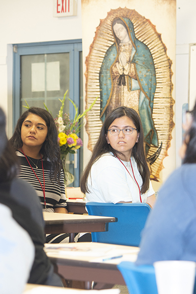 Los adultos jóvenes escuchan mientras uno de sus compañeros hace una pregunta a uno de los oradores en el Instituto Veraniego de Liderazgo para Jóvenes Latinos.