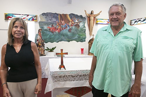 Nancy McCrosson, bookkeeper and property manager at St. Peter, poses with Knights of Columbus John Krieger in front of the altar salvaged from the chapel of the church. Behind them is a replica of the painting that adorned the church's sanctuary.