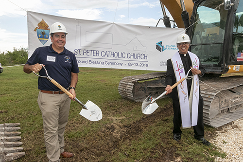 David Prada, senior director of Building and Property for the Archdiocese of Miami, and Father Jesus "Jets" Medina, parish administrator, pose in front of the construction equipment signals the demolition and reconstruction of St. Peter Church in Big Pine Key.