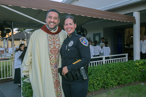 El P. Robert Ayala, párroco de St. Matthew y uno de los tres capellanes de la policía de Hallandale Beach, posa para una foto con la jefa de policía de Hallandale Beach, Sonia Quiñones, antes de la Misa del 60Âº. aniversario de la parroquia.