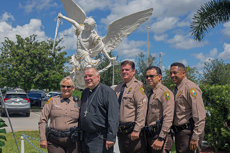 Posing for a photo in front of the St. Michael the Archangel statue at Our Lady of Guadalupe Church in Doral, after the celebration of the Blue Mass, from left: Miami-Dade Police Officer Mary Stahl; Archbishop Thomas Wenski; Steadman Stahl, president of the South Florida Police Benevolent Association; Alfredo Ramirez, deputy director of the Miami-Dade Police Dept.; and Miami-Dade Police Lt. John Jenkins.