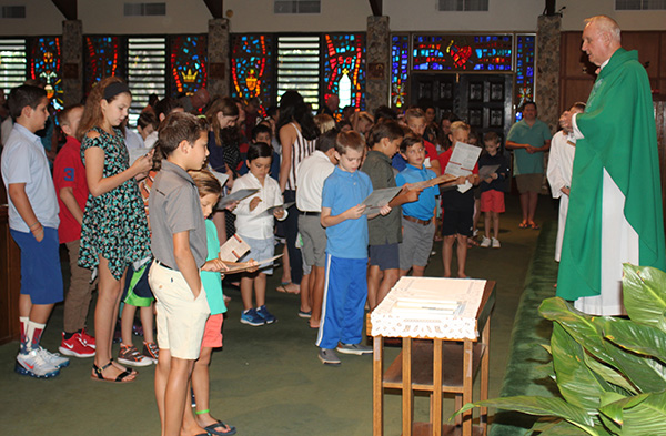 Msgr. Vincent Kelly calls the children of the parish to the altar as he celebrates the family Mass Aug. 25. The children are all enrolled in religious education, an important ministry of the parish that has continued to grow over the past 50 years. Religious education programs are part of the parish's mission to spread and pass along the faith to the generations.