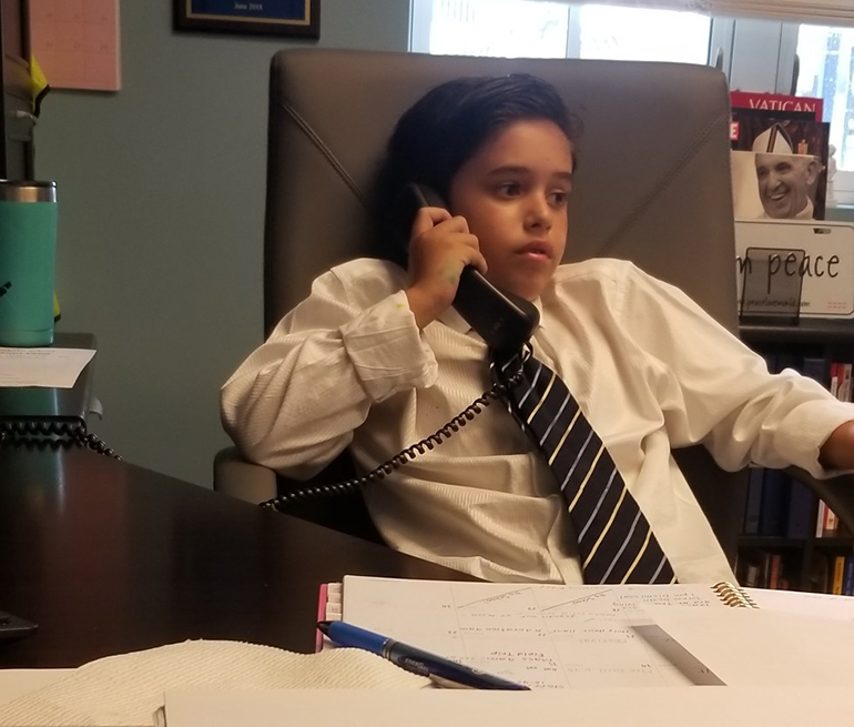 Diego Martinez, a fifth-grader at Blessed Trinity School in Miami Springs, takes a phone call while sitting in the principal's chair Oct. 2.