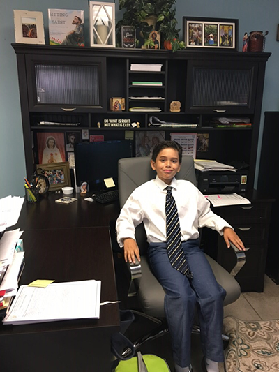 Diego Martinez, a fifth-grader at Blessed Trinity School in Miami Springs, sits in the principal's chair Oct. 2, doing his job as principal for a day. His parents literally "won" him the job during a raffle at last year's fashion show to benefit the school.