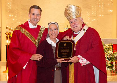 Archbishop Thomas Wenski and Msgr. David Toups, left, rector of St. Vincent de Paul Regional Seminary in Boynton Beach, recognize Mother Adela Galindo, founder of the Servants of the Pierced Hearts of Jesus and Mary, just before the Friends of the Seminary annual dinner Oct. 18, 2019.