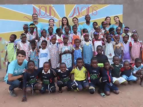 Hope for Kasai missionaries from South Florida pose with children from the village of Mpiana Nita in front of the mural painted by Our Lady of Lourdes Academy student Emma Uddenberg. It reads, "We have hope" in French.