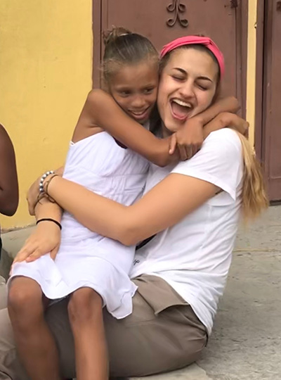 La misionera de Amor en Acción, Lucia Pannunzio, recibe un fuerte abrazo de una nueva amiga que hizo durante un viaje misionero, en la República Dominicana, este verano.