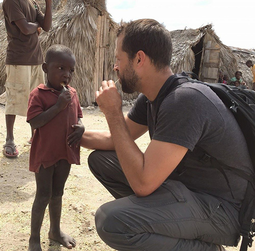 Andres Novela (right) shares a yummy treat with a new friend during a mission trip with Amor en Accion to Haiti.