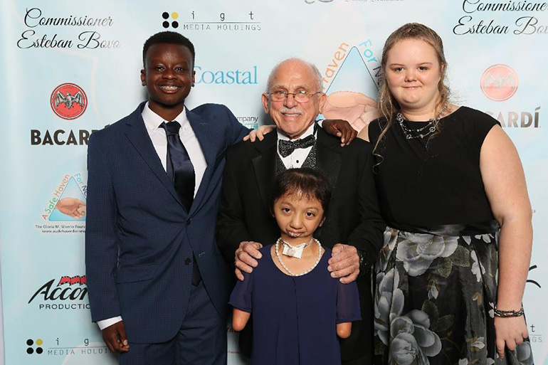 Nick Silverio, center, poses with several of the children saved through the intercession of A Safe Haven for Newborns: Kristopher, left, Milagros, center, and Gloria Hope, right.