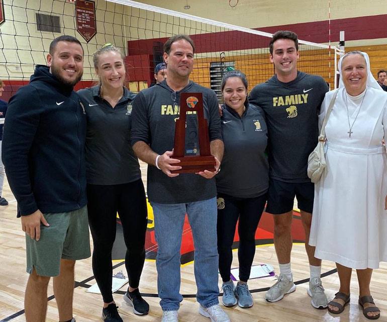 Immaculata La Salle girls volleyball coaches, trainers, supporters and Principal Sister Kim Keraitis, FMA, pose with their trophy after the Lady Royals won the 2019 Girls Volleyball District Championship in 4A District 15 on October 17 against MAST Academy.