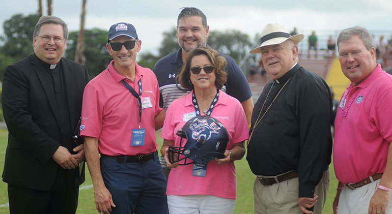 St. Thomas University President David Armstrong, far right, and Miami Archbishop Thomas Wenski present Marc and Ann Cannon of AutoNation with a Bobcats football helmet to thank them for their support of STU's Breast Cancer Awareness Game, Oct. 26, 2019. Also pictured are Schoenstatt Father Jesus Ferras, left, administrator of St. Kieran Parish in Miami, and Alfred Caballero, STU's director of Major Gifts & Sponsorships for Athletics (back).
