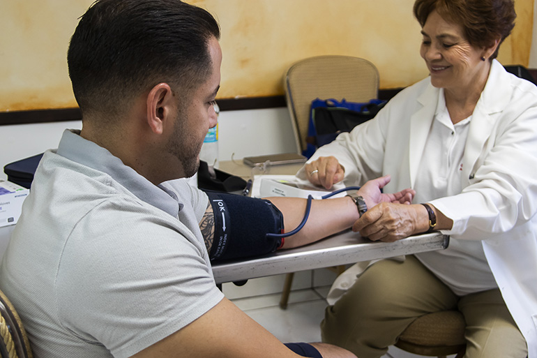 Dr. Gladys Lopez was one of several doctors and medical personnel who volunteered at the free Health Fair at Our Lady of Charity National Shrine Nov. 2. Dr. Lopez began each screening by checking each patient's blood pressure.