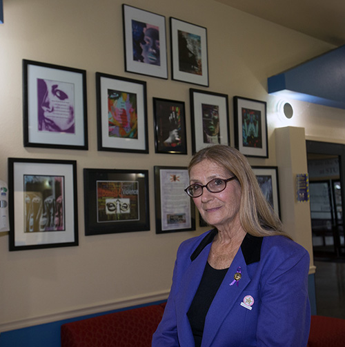 Susan Buzzi, victims advocate, educator, and retired police officer poses with her photographs after giving a talk at St. Thomas University on domestic abuse, Oct. 17, 2019.