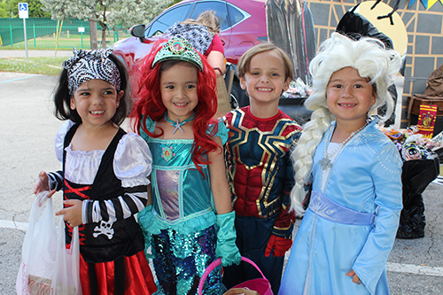 Students from St. Michael the Archangel School dressed as a pirate, Ariel from The Little Mermaid, Spiderman, and Elsa from Frozen are all smiles as they begin trick or treating at the school's third annual trunk or treat event Oct. 31.