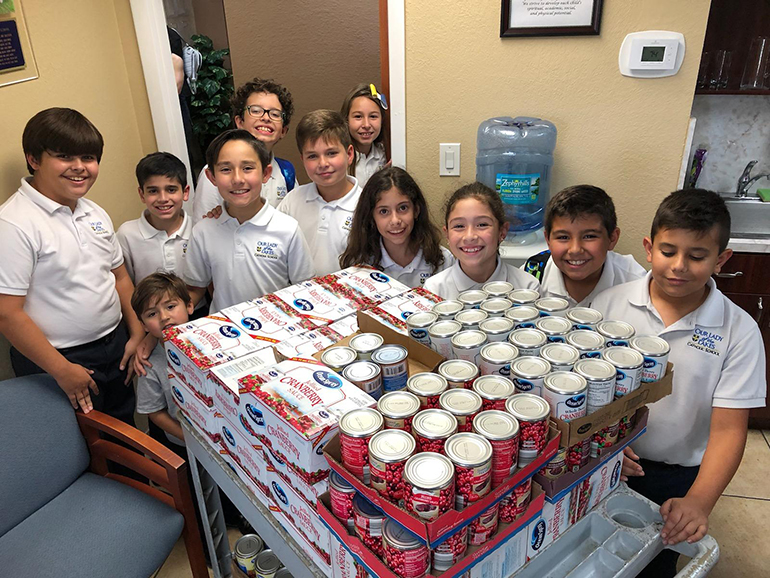 Fourth graders from Our Lady of the Lakes School pose with some of the food items donated to the parish and school's annual Thanksgiving drive. From Nov. 1 through Nov. 25, the Miami Lakes community collected enough to provide Thanksgiving meals to 710 families in neighborhoods surrounding Miami Lakes. The families received food and supermarket gift cards. The food bags included marshmallows, stuffing, dried beans, instant potatoes, corn, yams, cranberry sauce, peas, green beans, rice and macaroni and cheese.