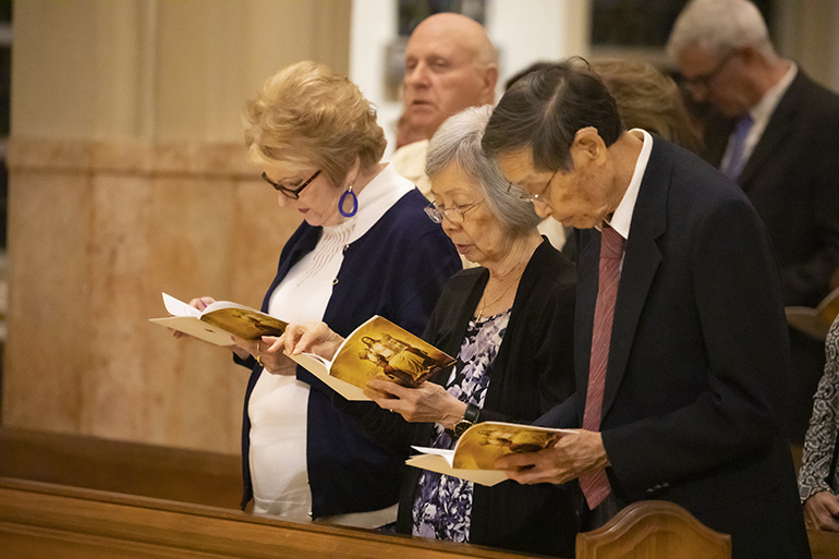 Truemin Chin, center, from the parish of Our Lady of Guadalupe in Doral, prays during the Thanks-for-Giving Mass celebrated at the Cathedral of St. Mary, Nov. 23, 2019. Chin received the One in Faith award from Archbishop Thomas Wenski.