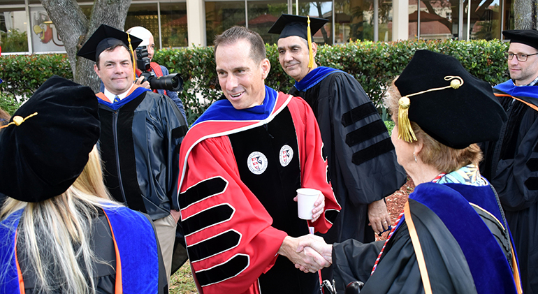 Mike Allen shakes hands with faculty members before his inauguration as president of Barry University.