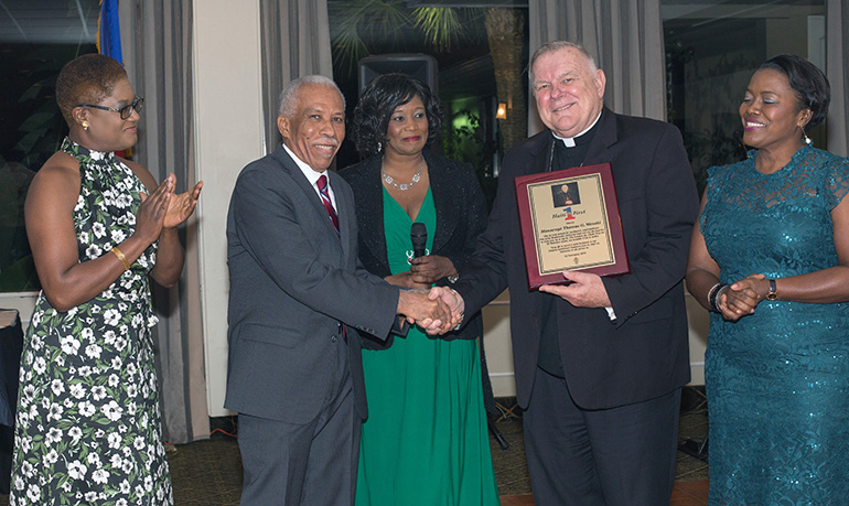 Archbishop Thomas Wenski shakes hands with Justin Manuel, Haiti First founder, as board members Yveline Auguste, Michel Soeurette and Blondine Laine look on. The archbishop was honored at the NGO's seventh annual Fundraising Cultural Night, Nov. 16, 2019 in Miami Shores.