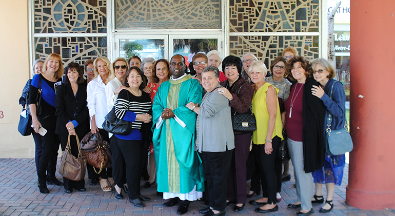 Members of Notre Dame Academy's class of 1969 pose with Father Reginald Jean-Mary, pastor of Notre Dame d'Haiti Church, which now occupies the site of their old school, after celebrating Mass with the community and visiting the school Nov. 17, 2019.