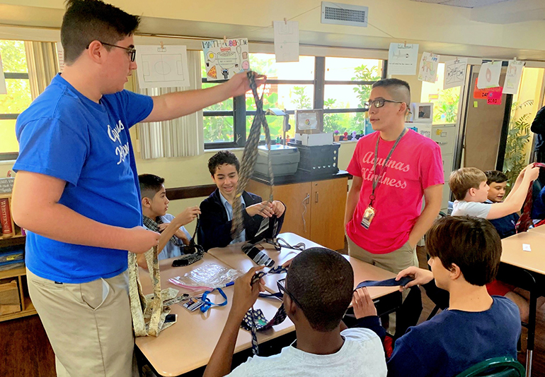 Joey Hagood hands a necktie to freshman Colby Kitson at St. Rose of Lima School, Miami Shores, as part of a presentation by the Aquinas Kindness club.