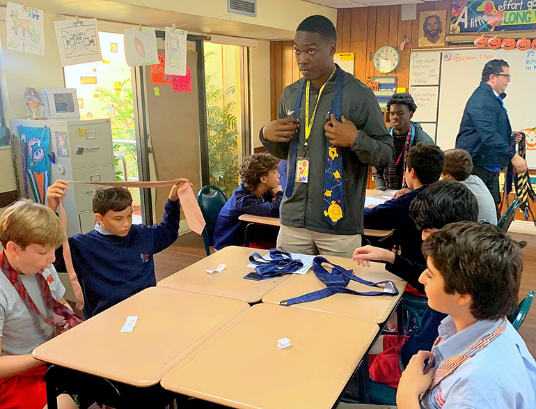 The'Andris Freeman of Aquinas Kindness shows students at St. Rose of Lima School, Miami Shores, how to knot a necktie. The skill is part of being a gentleman, he says.