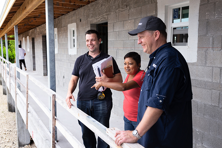 Devika Austin, center, chief administrative officer for Catholic Charities of the Miami Archdiocese, looks at the site of a Catholic Charities-sponsored St. Bede’s Village workforce development facility under construction in Key West. On the left is project architect, Joe Scarpelli, and on the right is Catholic Charities board member and CPA Craig Armstrong, a member of St. Louis Parish in Pinecrest.