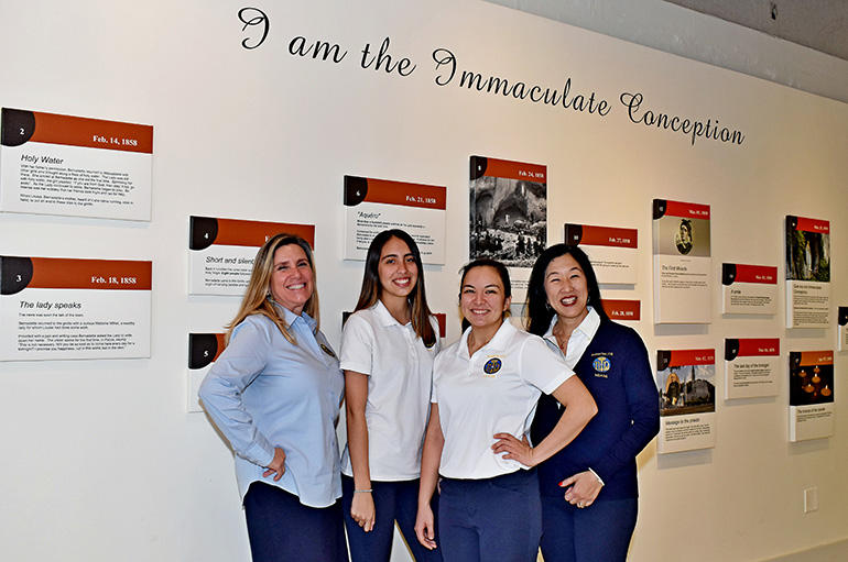 Members of Hospitalité de Miami gather at the timeline wall at Our Lady of Lourdes Church in Miami. From left are Cristina Fernandez, Daniella Perez, Gabriella Rodriguez and Michelle Rodriguez.