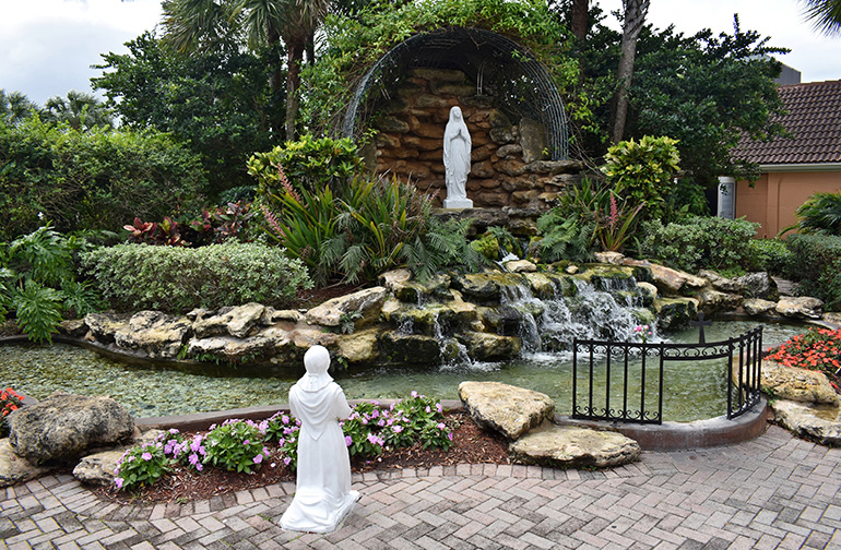 A statuette of St. Bernadette kneels at a grotto and waterfall meant to evoke the shrine at Lourdes, France.