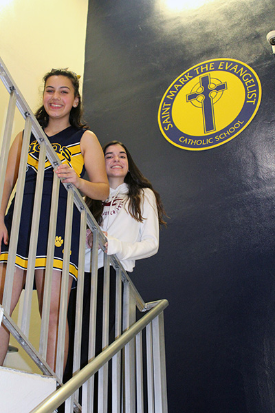 St. Mark the Evangelist School seventh graders Olivia Perez and Katherine Cue pose in one of the stairways of the school. Olivia and Katherine worked together to create a video history of their school, now celebrating its 25th anniversary, which was screened at the school gala held Jan. 24, 2020.