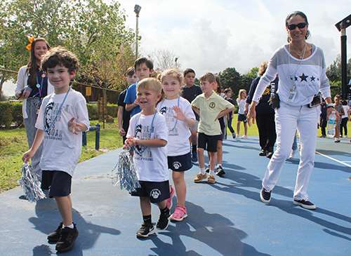 St. Mark School Principal Teresita Wardlow accompanies PreK4 students as they depart the school basketball court after the pep rally held Jan. 24, 2020 to celebrate the school's 25th anniversary.