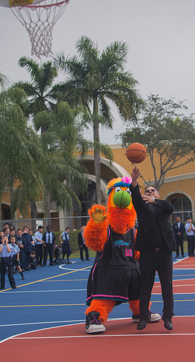 Mother of Our Redeemer's pastor, Father Juan Pedro Hernandez, shoots at the basket as Burnie, the Miami Heat mascot, looks on, part of the fun that followed the blessing of the school's new basketball-volleyball court, Jan. 27, 2020.