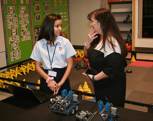 St. John Neumann seventh grade student Priscilla Fernandez demonstrates the coding process for the Vex robots to school board member Monica Inguanzo.