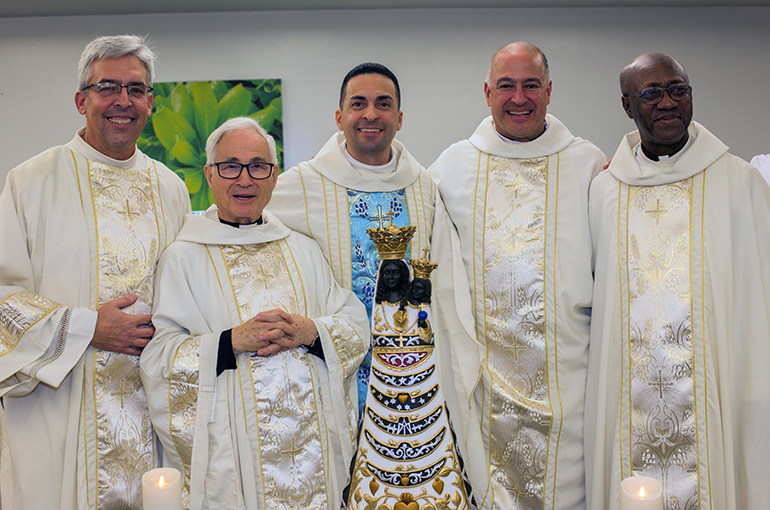 Posan con la imagen de Nuestra Señora de Loreto, desde la izquierda: El diácono Ernie Sosa, el P. Urbano Monedero, el P. José Alfaro, el P. Elkin Sierra y el P. Lesly Jean. El P. Monedero, es el capellán del aeropuerto de Madrid, trajo la imagen a Miami como parte de una peregrinación jubilar en todo el mundo. Nuestra Señora de Loreto es la patrona de las personas involucradas en la aviación, así como los constructores y trabajadores de la construcción.