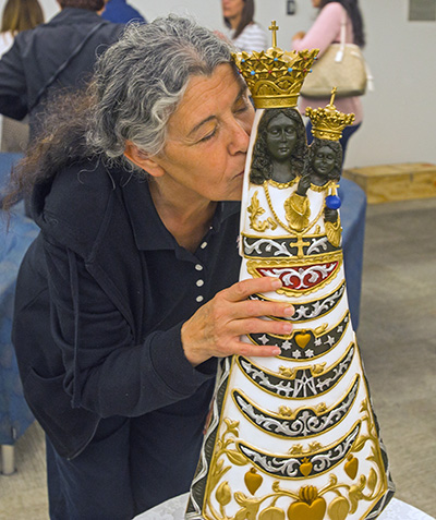 Rachel Ghalloub, a parishioner at Blessed Trinity in Miami Springs, kisses the image of Our Lady of Loreto after taking part in the Mass celebrated upon her arrival at Miami International Airport, Feb. 17, 2020.