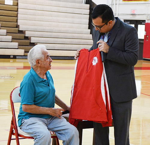 Cardinal Gibbons principal Oscar Cedeño presents a Gibbons fleece jacket to Holocaust survivor Bernard Igielski after he shared his story of survival with the high school's juniors and seniors.