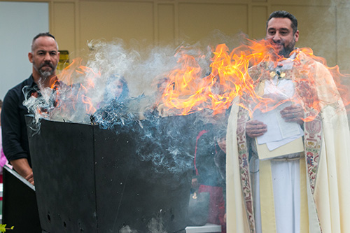 Father Robert Ayala, pastor, and students in the religious education program at St. Matthew Church, Hallandale Beach, watch as the palms from last year's Palm Sunday are turned into the ashes for this year's Ash Wednesday.