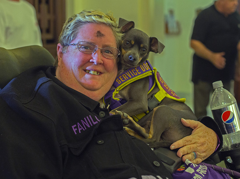 Kim Greager, who is disabled, holds her service dog, Barry Manilow, Jr., after attending Ash Wednesday Mass with Archbishop Thomas Wenski at St. Anthony Church in Fort Lauderdale, Feb. 26, 2020.