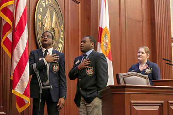 Brothers Christopher Sykes, left, and Corey Sykes of Monsignor Pace High pledge allegiance to the American flag during a recent internship in Tallahassee.