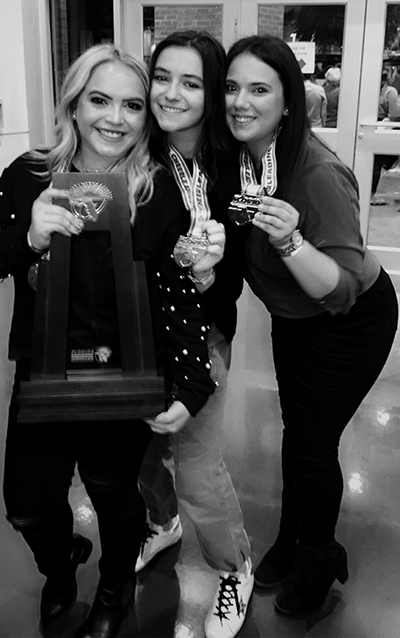 Immaculata-La Salle's cheerleading coaches, from left, Coral Buxeda and her assistant coaches, Emily RodrÃ­guez and Karyn Hernandez, show off their medals and championship trophy after winning the school's first state title in competitive cheerleading Feb. 1, 2020, in the Class 1A extra-large non-tumbling division.