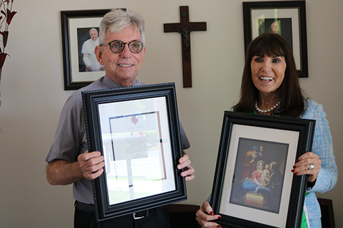 Catherine Wiley, founder of the Catholic Grandparents Association, presents Father Michael Greer, pastor of Assumption Parish in Lauderdale-By-The-Sea, with an image of the Holy Family and a framed prayer for grandparents. Father Greer hosted a meeting at his church, Feb. 20, 2020, to launch the new grandparents ministry in the Archdiocese of Miami.