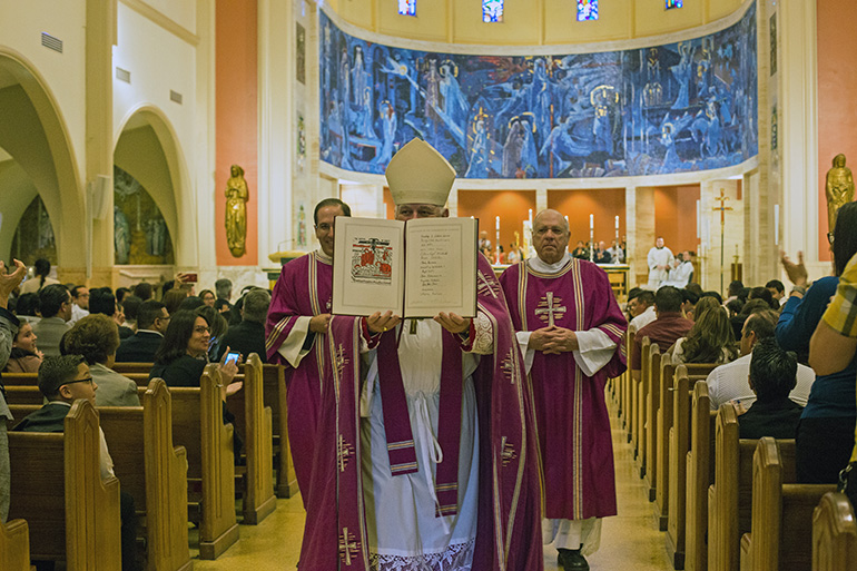 Archbishop Thomas Wenski displays the names signed into the Book of the Elect during one of the two Rite of Election ceremonies held March 1, 2020, at St. Mary Cathedral.