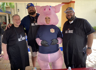Here come the judges: St. John Neumann pastor Msgr. Pablo Navarro, along with NBC 6 and Telemundo 51’s resident local foodie Roberto “Kiko” Suarez, and Father Matthew Gomez pose with a parishioner in pig costume at the Swine and Dine Lechon Cook-off and Bazaar on Feb. 22. Funds from the event went towards the school's new STEM innovation lab.